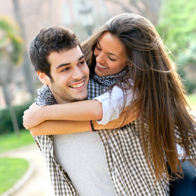 Close up portrait of attractive young couple piggybacking outdoors.